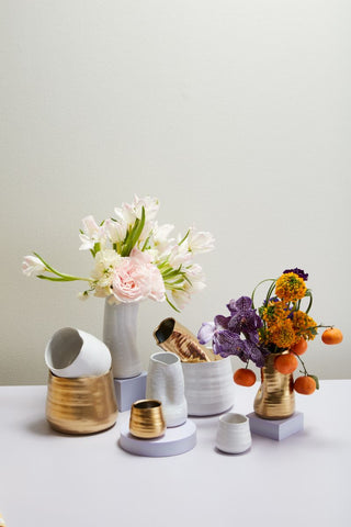 a bunch of white and gold vases with flowers in them