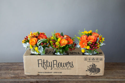 FiftyFlowers box holding three orange centerpieces