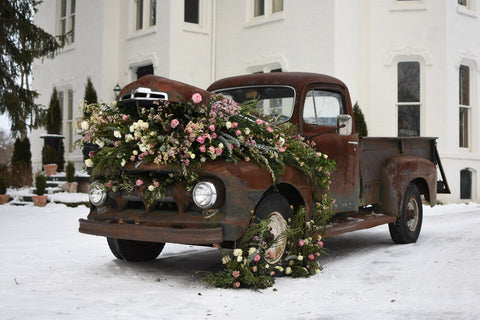 vintage car in wedding with pink and green flowers in hood of car