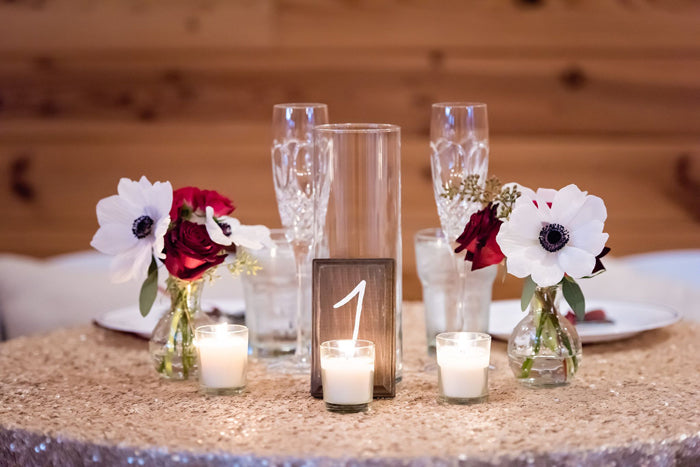 simple flower arrangements were paired with candles and other decor on this table to stay within budget