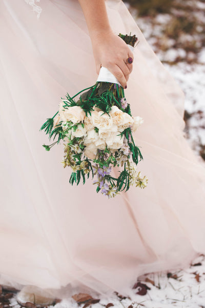 bride holding white and green winter wedding bouquet