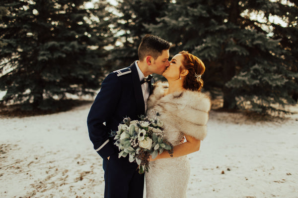 bride and groom kissing during winter wedding holding bridal bouquet