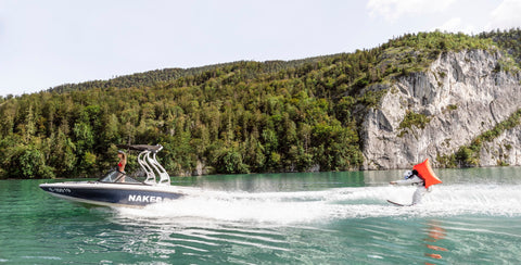 Ein Mann fährt mit den Wasserski und wird von einem Boot nachgezogen. 