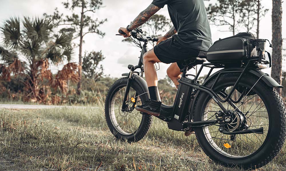 A man is riding a Explore e-bike with a 26-inch wheel outside