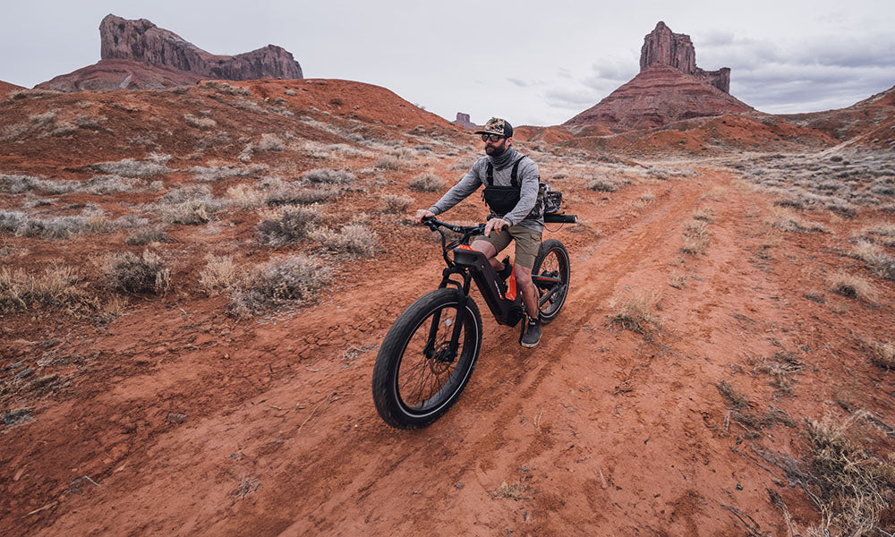 A man is riding a Hero electric bike off-road