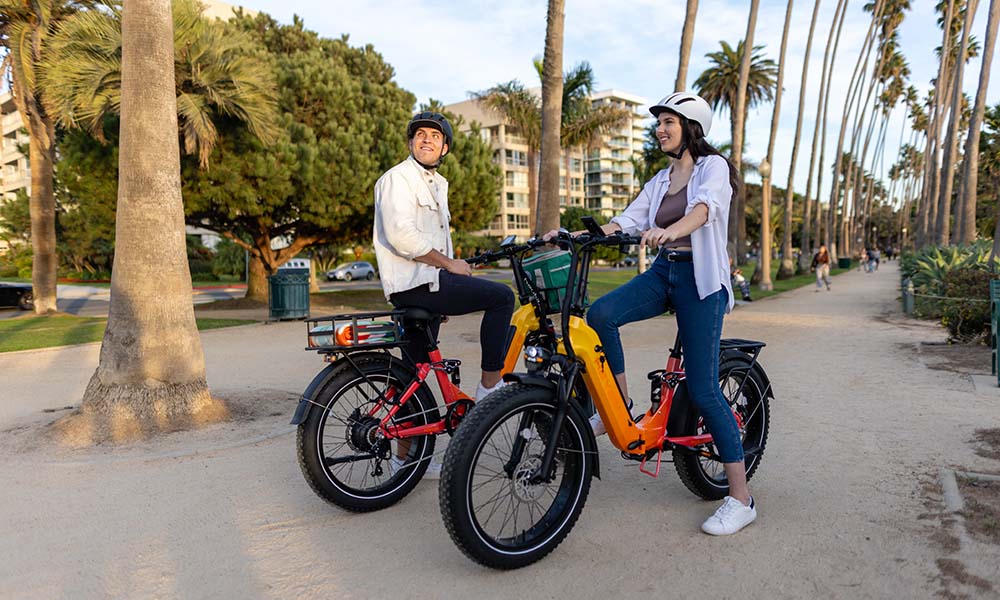 a man and girl are riding Horizon full-suspension ebike by the beach