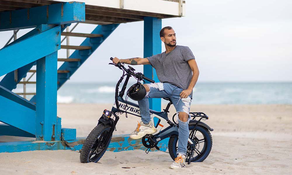 a man is riding Tyson fat tire bicycle on the beach