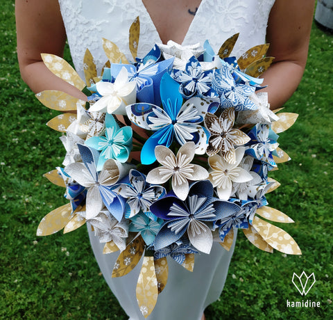 Bouquet en origami bleu, blanc et doré porté par une mariée