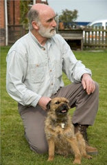 Canny Collar inventor Brian Smith kneeling with a Border Terrier