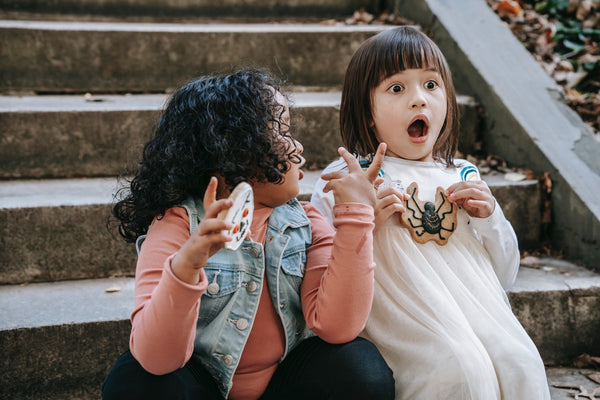 Two little girls holding Halloween sugar cookies 