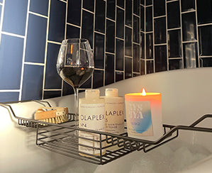 scented candle, bubble bath, red wine ola plex shampoo and conditioner blue metro tiles bathroom tiles dry body brush