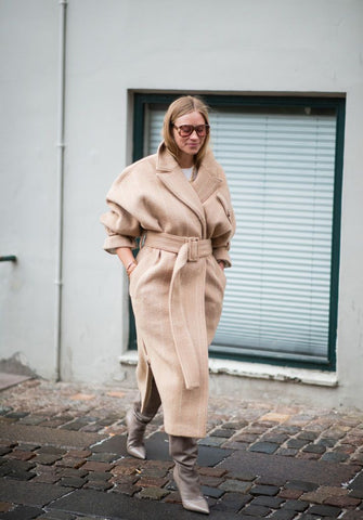 woman wearing winter fashion trend belted coat to keep warm for her winter date night