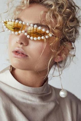 woman wearing pearl sunglasses with pearl earrings for the pearlcore trend