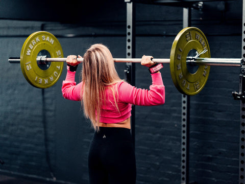 Woman using Versa Gripps to do an overhead press in the gym