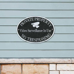 cast aluminum security camera sign on the side of a house