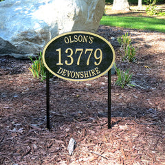 oval shaped address plaque mounted with lawn spikes in landscape