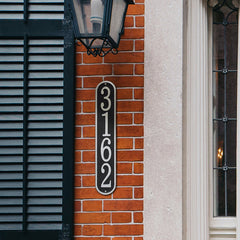 vertical house number plaque mounted on brick