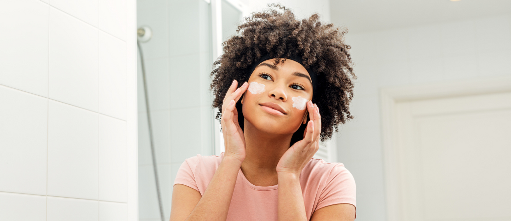 woman using skincare products in mirror 