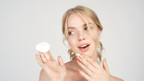 Woman with cotton pads applying skincare