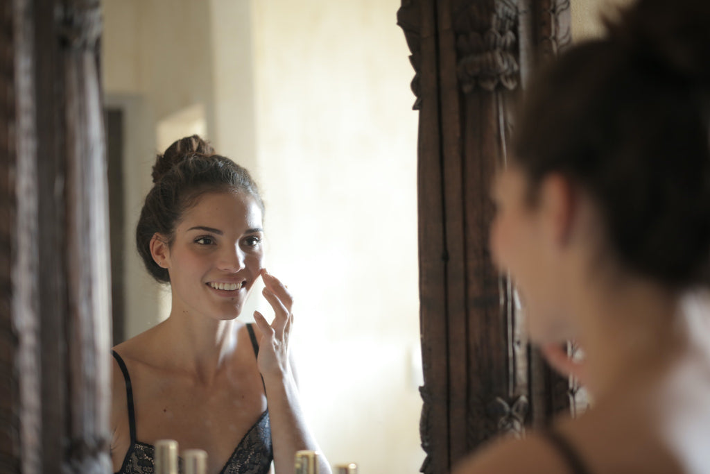 woman applying skincare product in mirror 