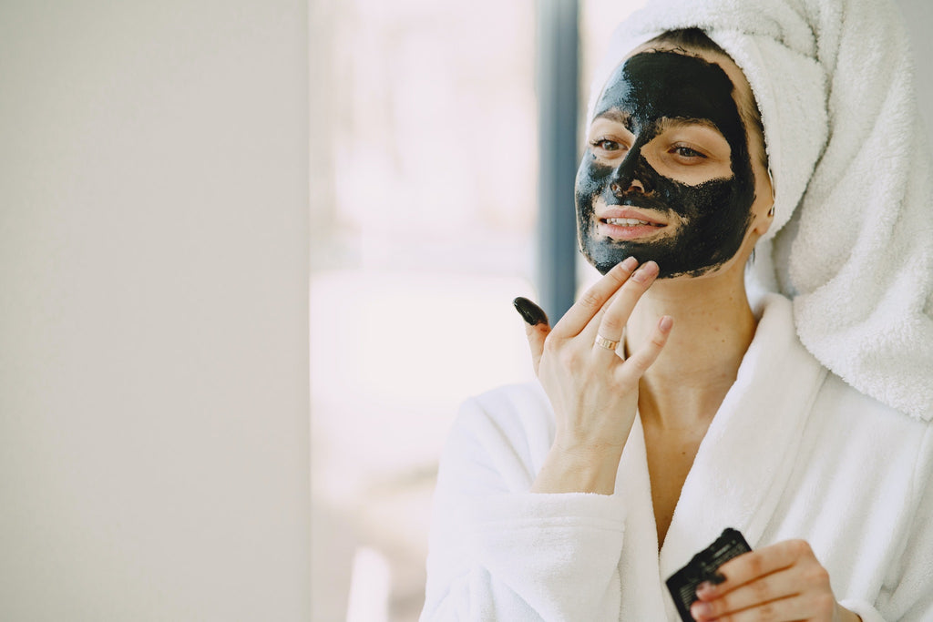 woman using face mask looking in mirror 