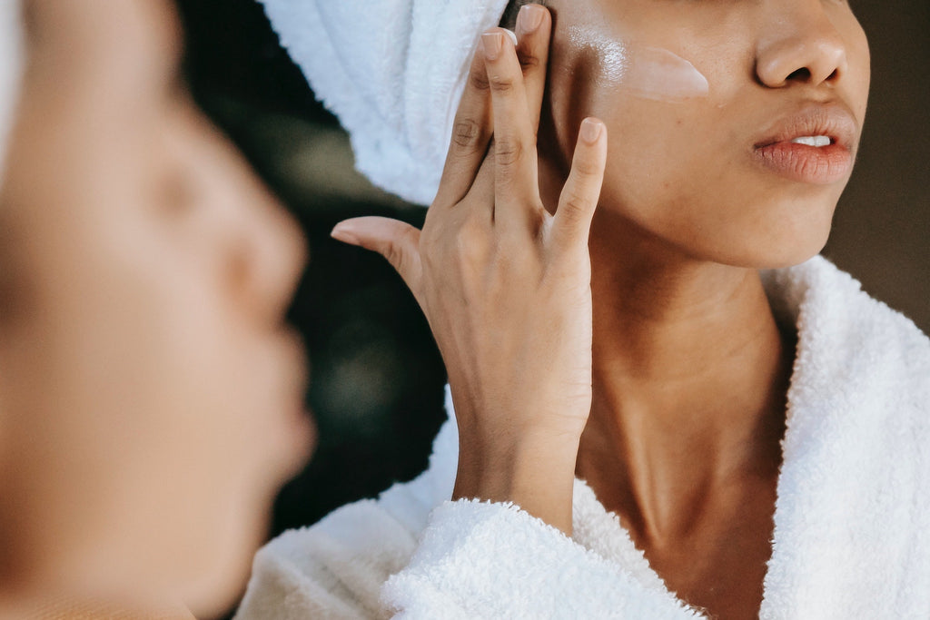 woman using gentle cleanser skincare product in mirror