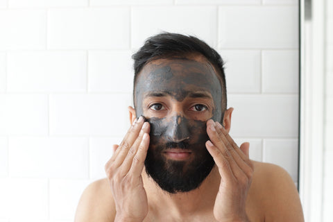 man applying face mask in mirror