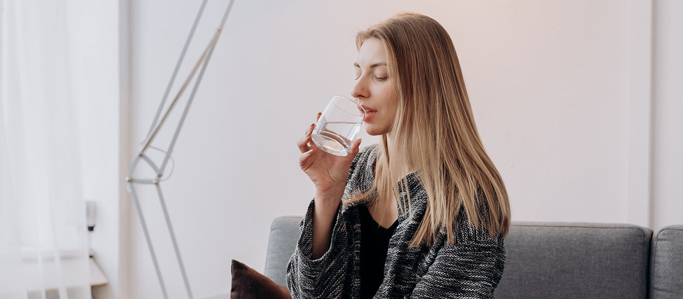 Frau trinkt aus Glas Wasser für Stoffwechsel anzuregen