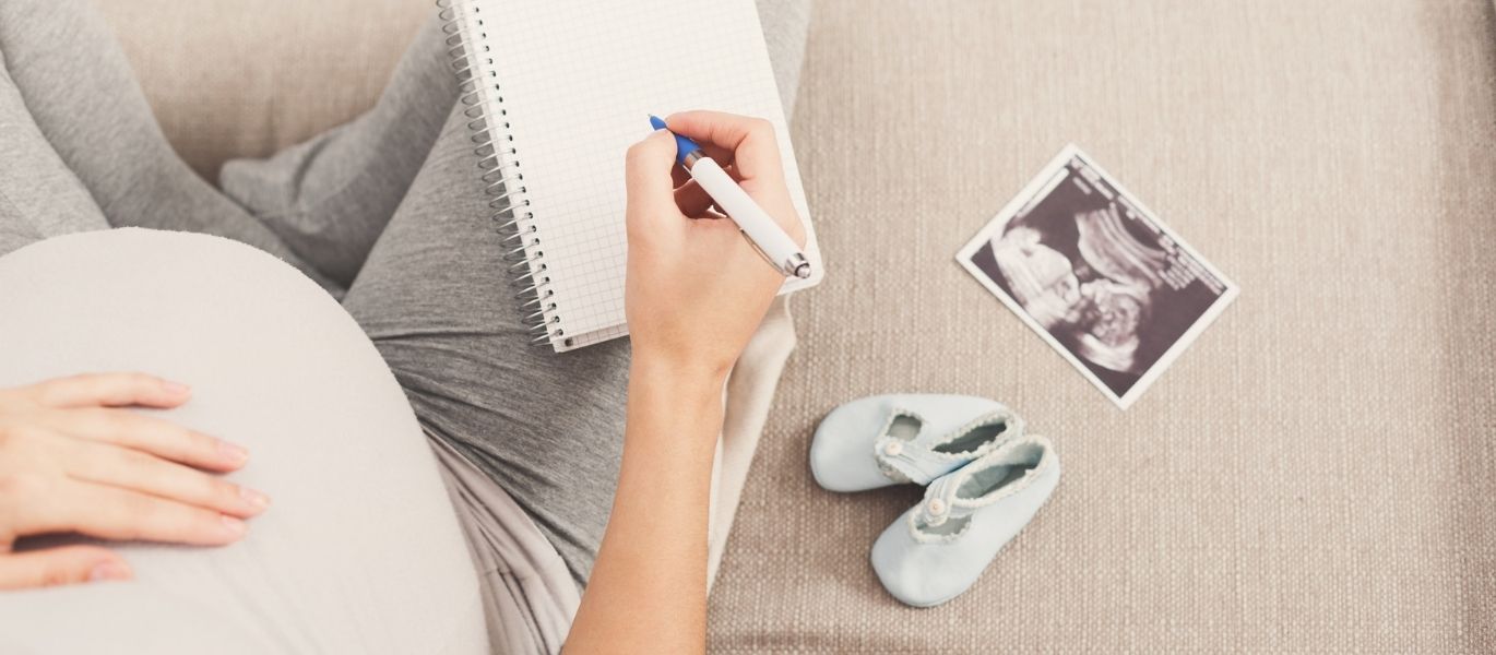 schwangere Frau schreibt etwas auf