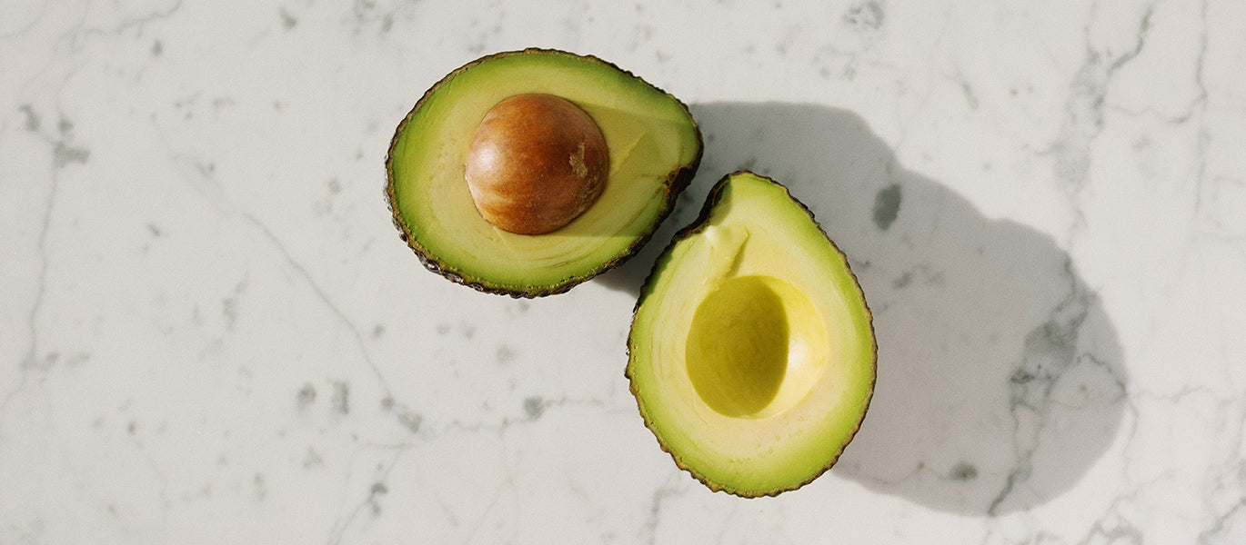 Avocados aufgeschnitten auf Marmor Struktur gute Fette gesunde Fette abnehmen mit gesunden Fetten