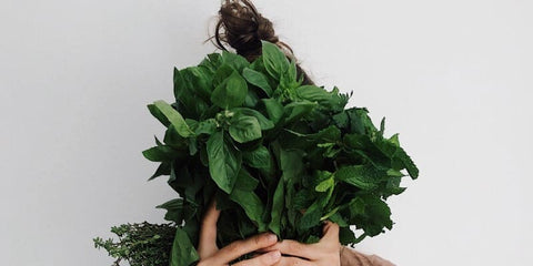 Vegane Ernährung - Frau mit Spinat vor dem Gesicht