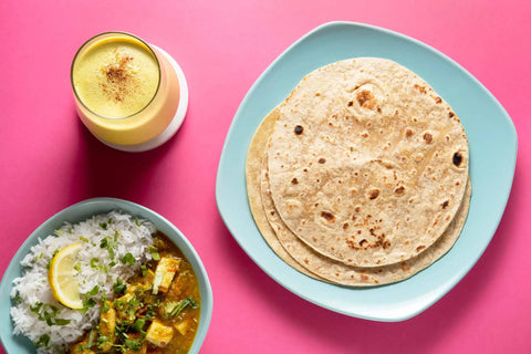 Wheat Chapati on a plate with a bowl of rice and mango shake in a glass