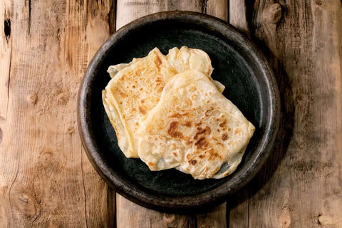 Guyanese Roti placed on a plate on a wooden table