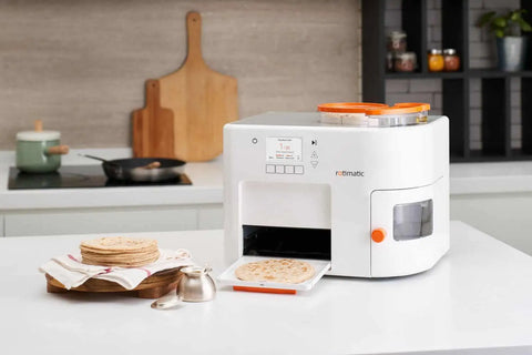Rotimatic machine placed on a table in the kitchen with rotis stacked on a wooden tray