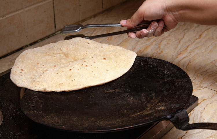 cooking roti fluffing on a pan