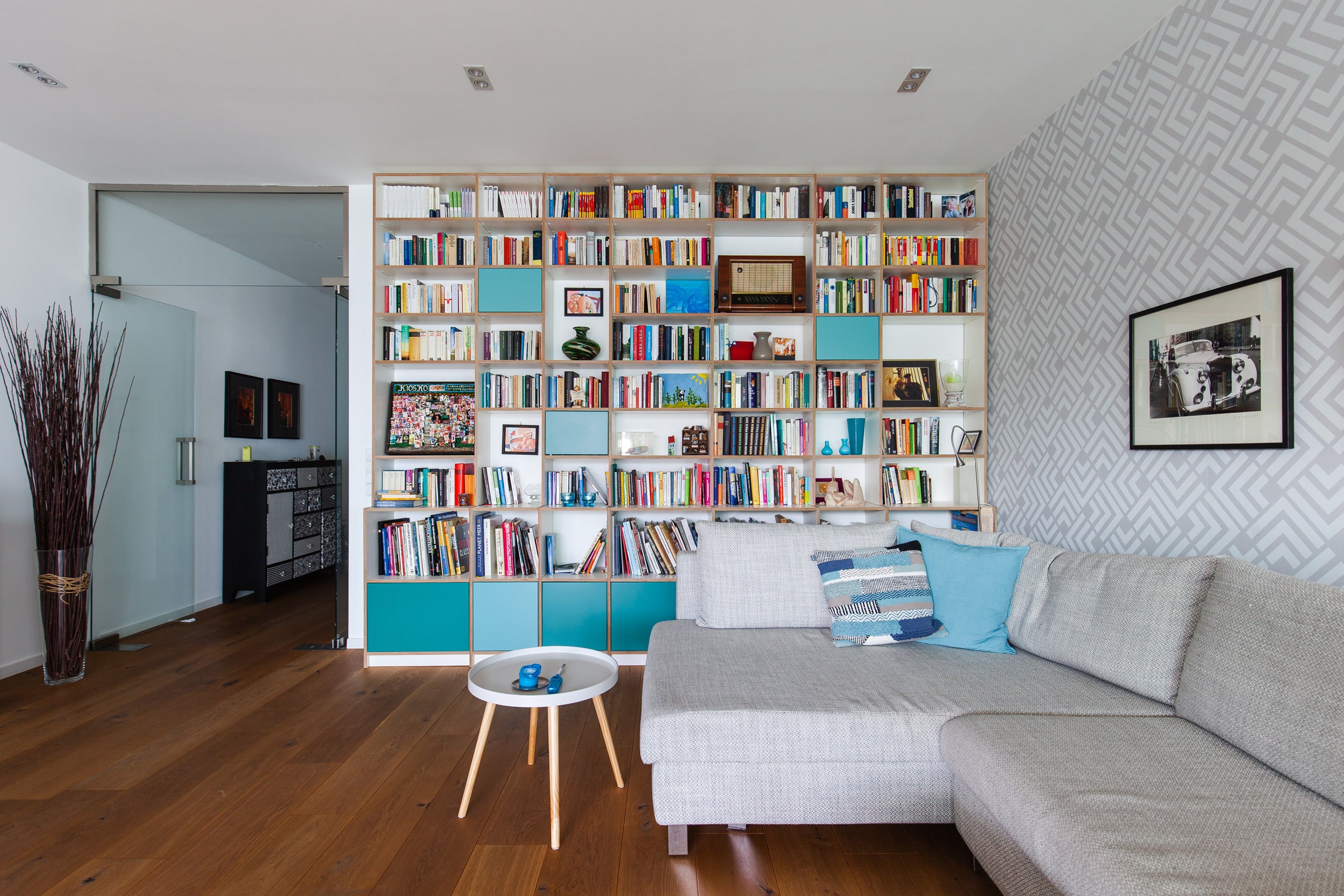 salon dans appartement avec canape gris et bibliotheque bois et bleue