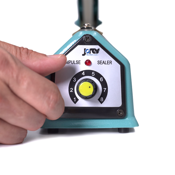 Person turning the seal timer knob on a manual impulse sealer to regulate the amount of time that heat is applied to the bag during the sealing process