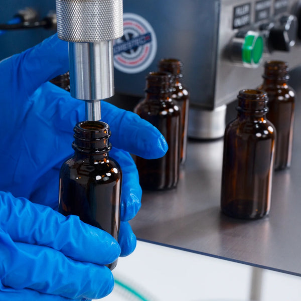 Nozzle of a piston filler packaging machine close to the opening of a container, ready to be filled with product