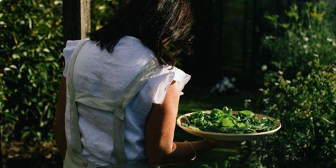 A lady in the garden holding a bowl of salad leaves