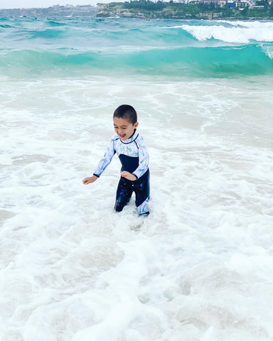 Boy having fun in water playing wearing a wetsuit on a cold day