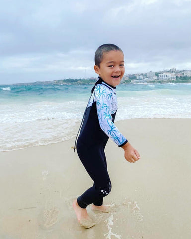 Boy playing in sand in wetsuit on a cold day