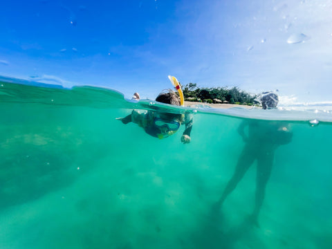 Boy snorkelling in blue waters in wetsuit