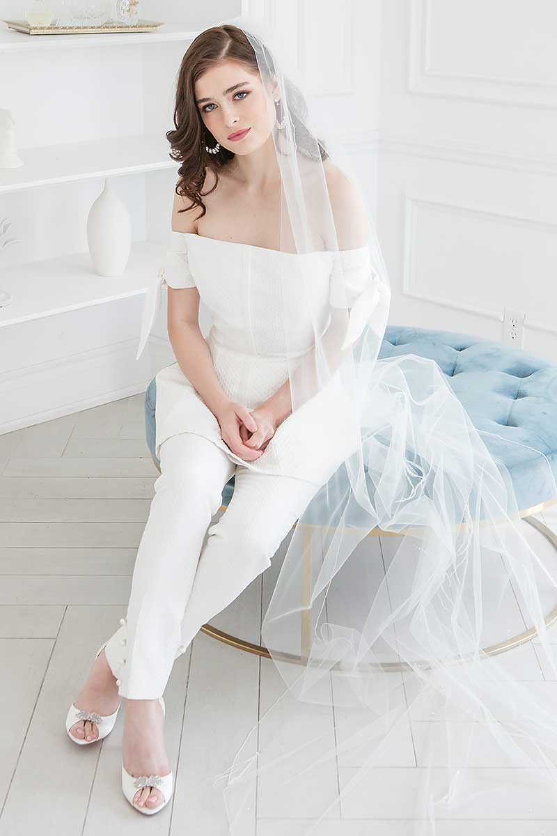 Bride seated wearing Angela Nuran shoes with cathedral veil and hoop earrings