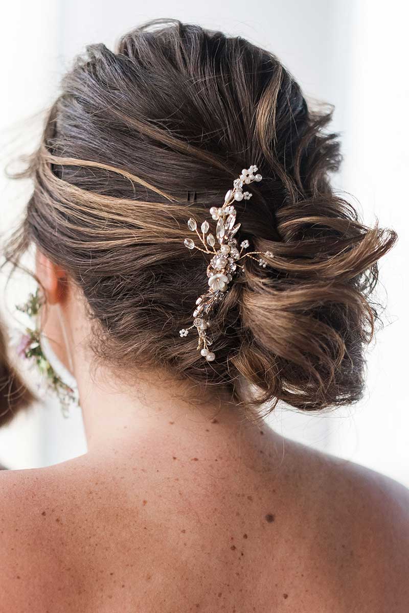 Head and shoulders of woman with messy bun updo and profile gold headpiece