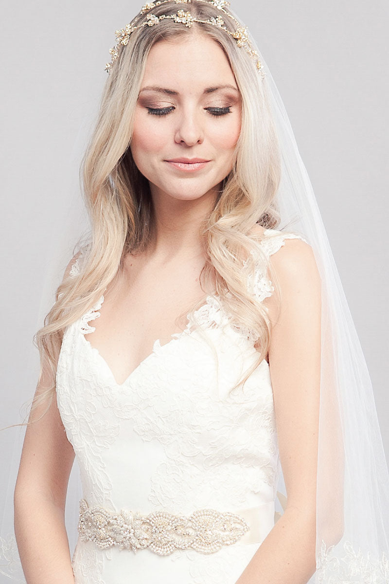 Boho chic bride wearing the satin ribbon Chanteuse Sash with a center flower of beaded petals and pearl accents from Laura Jayne