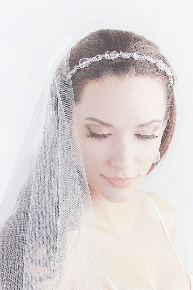 Romantic bride with downward gaze wearing Rafaella headband with CZ pear oval stones by Laura Jayne