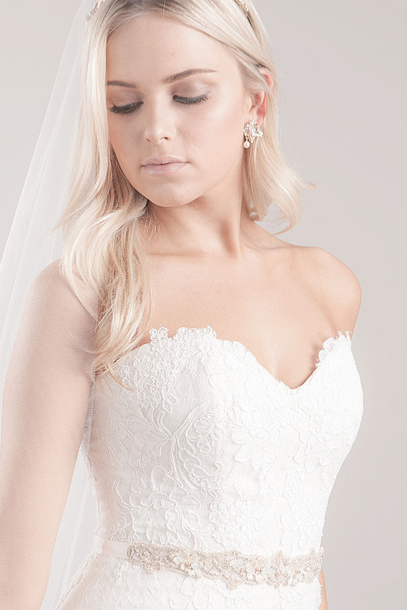 Pretty, modern bride wearing a lace wedding dress with the pearl and satin Trista Leaf Sash from Laura Jayne