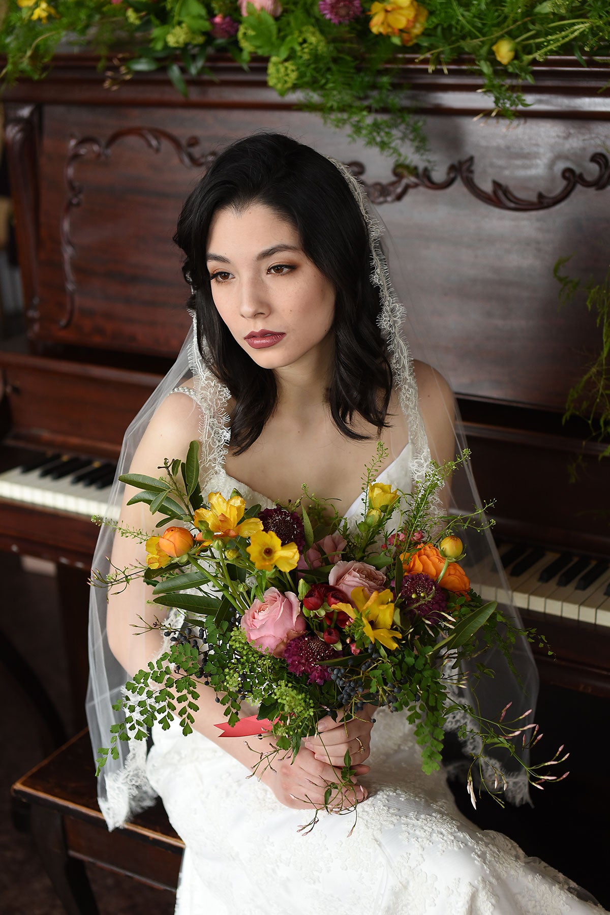 bride wearing lace veil and holding a flower bouquet 