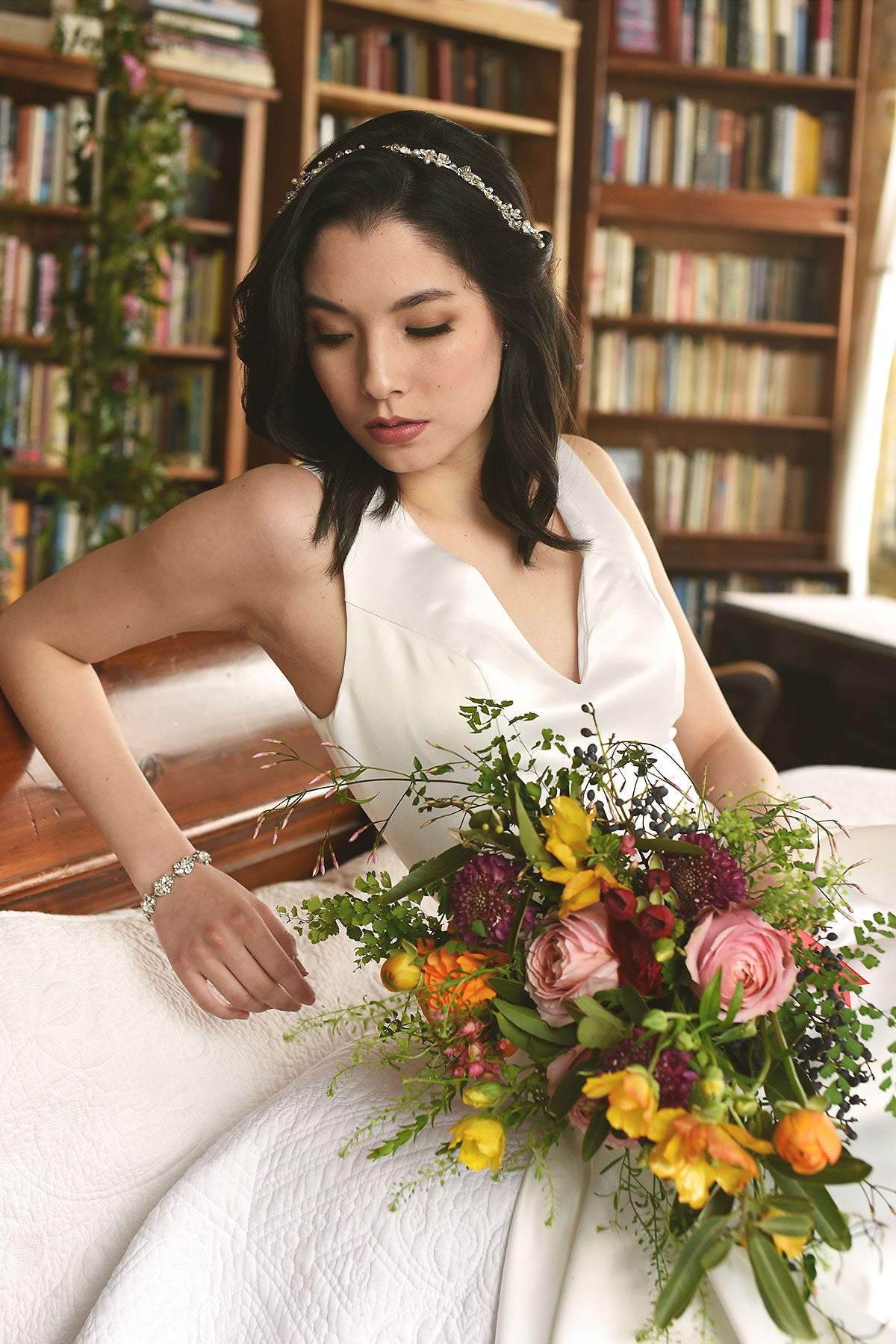 bride sitting on coach holding a wedding bouquet 
