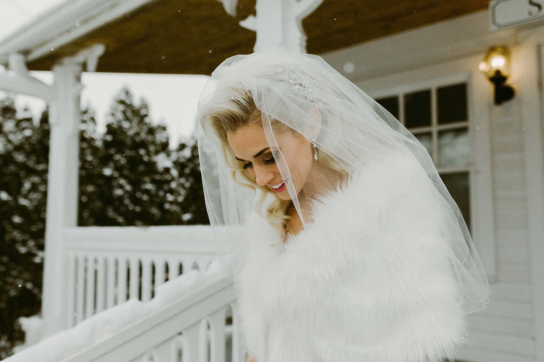 happy bride outdoors wearing fur and veil 